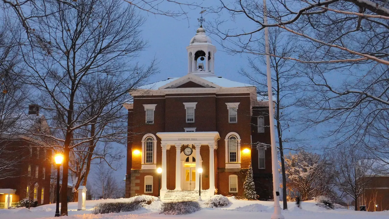 Hathorn Hall and its bell tower at dusk in winter snow at Bates College in Lewiston, Maine