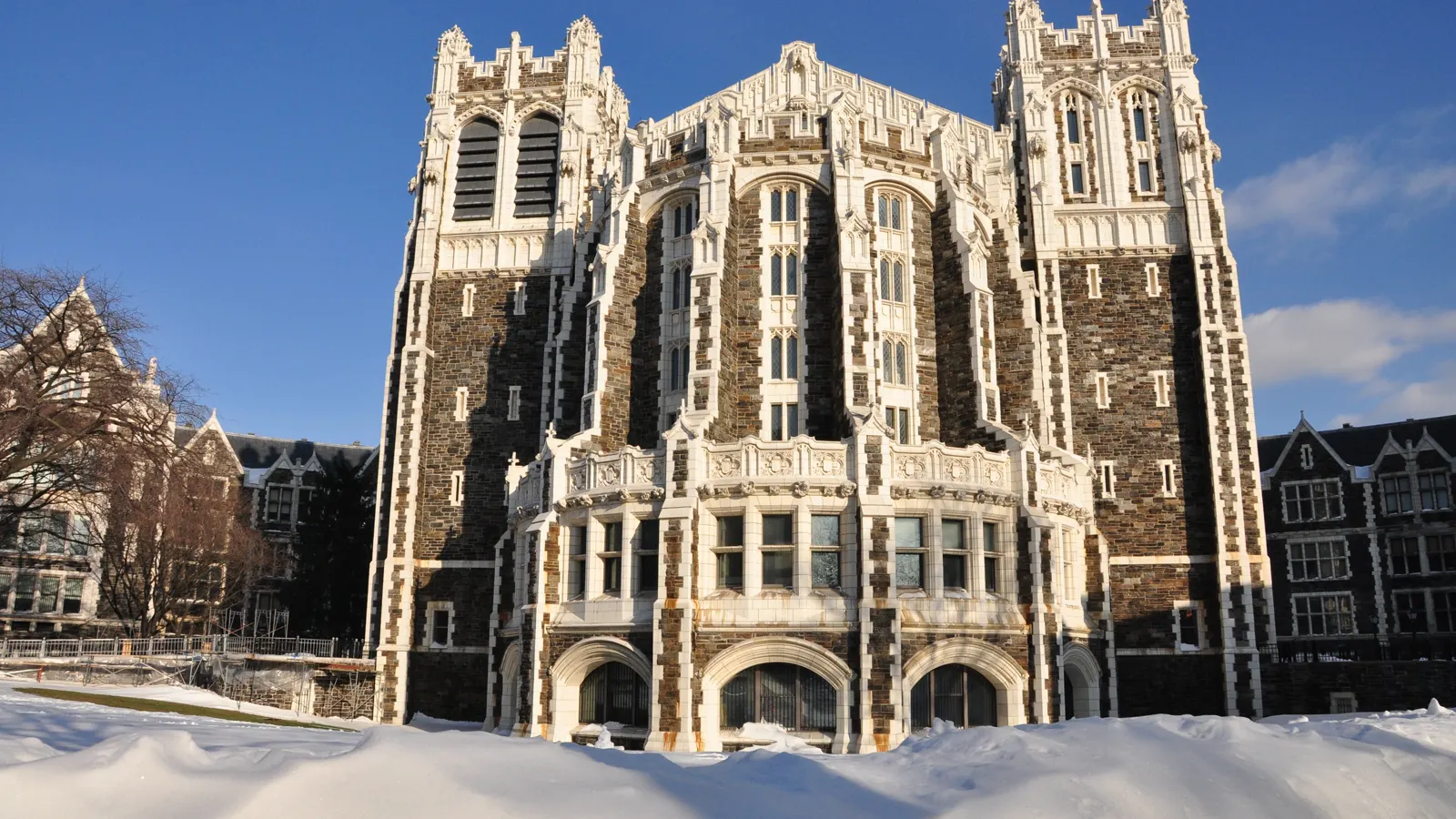 Shepard Hall, the dark stone and white terracotta Gothic building at City College of New York, with snow on the lawn