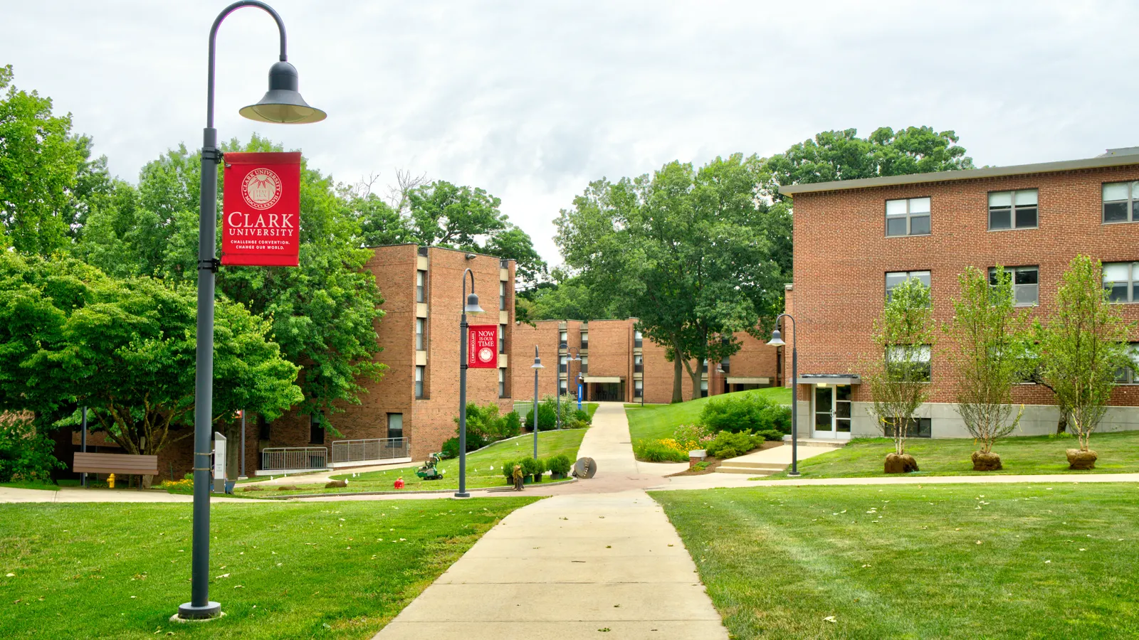 Brick residence halls along a walkway with Clark banners at Clark University in Worcester, Massachusetts