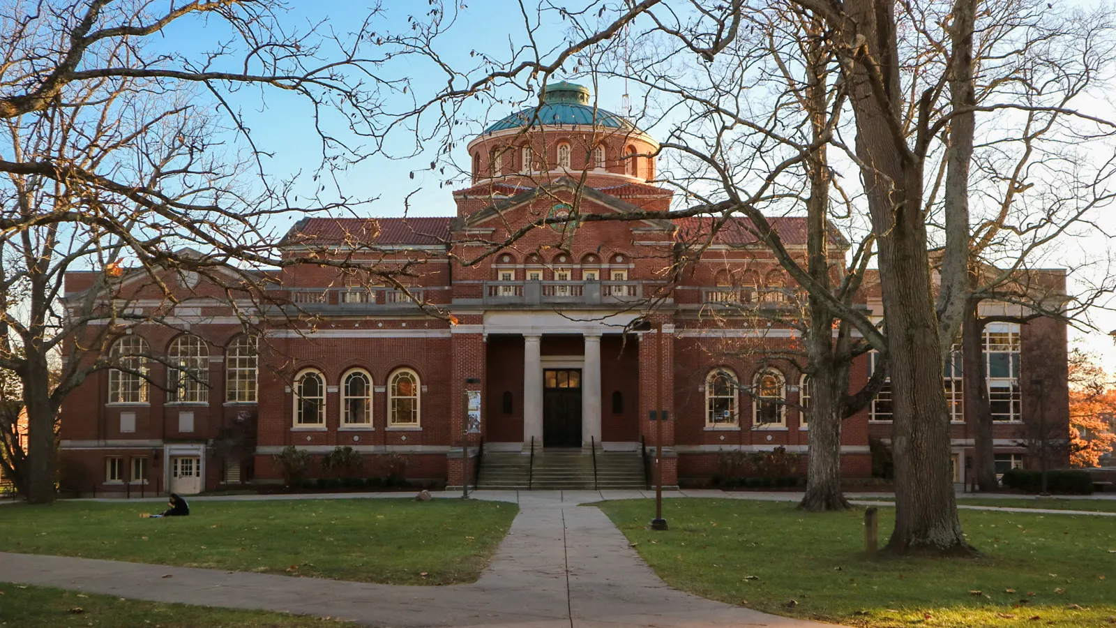 Alumni Hall, a red brick building with a green dome, seen down a tree-lined walk on the Miami University campus in Oxford, Ohio
