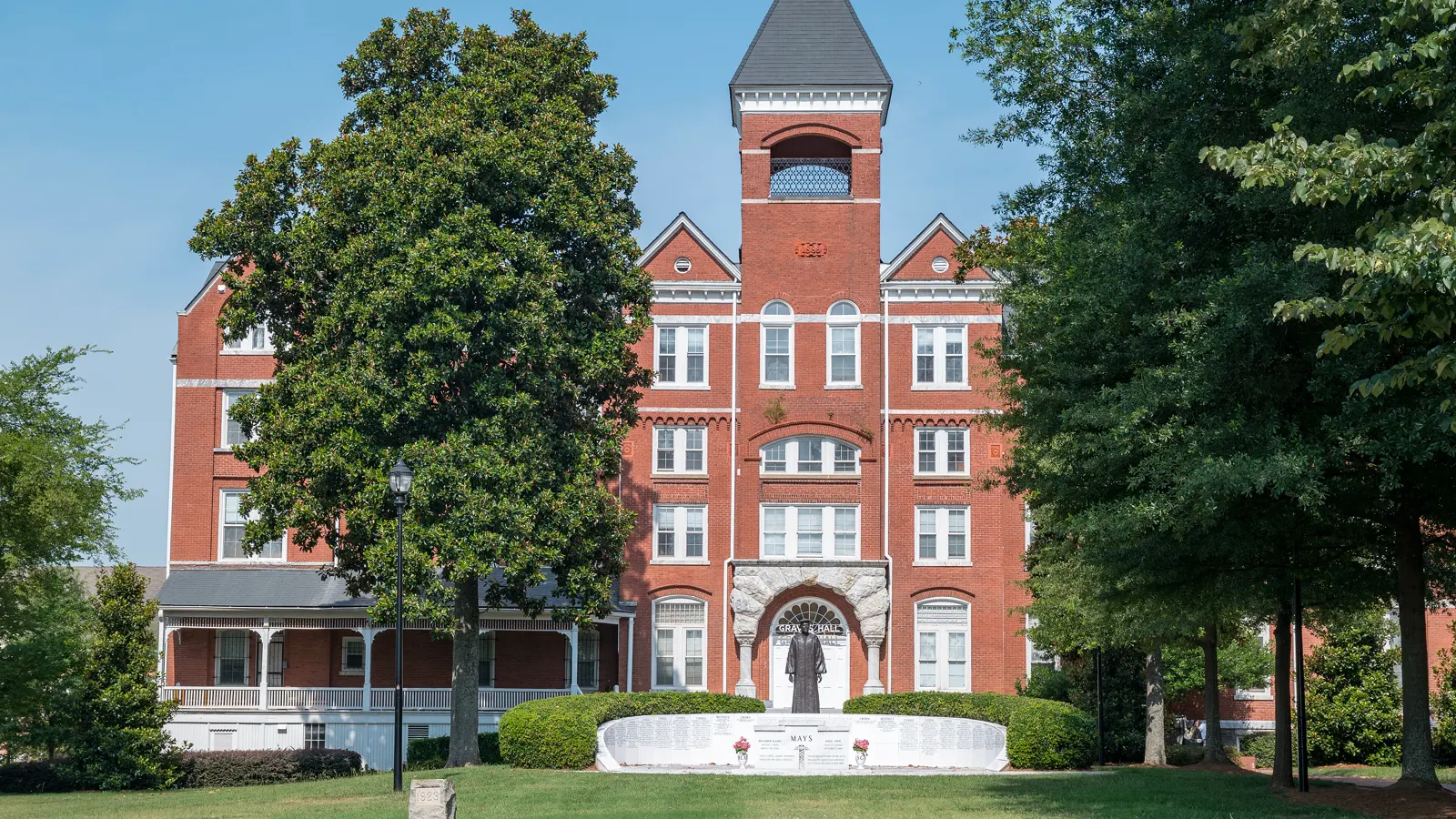 Samuel T. Graves Hall, a red brick building with a central tower, behind a statue and shade trees at Morehouse College in Atlanta