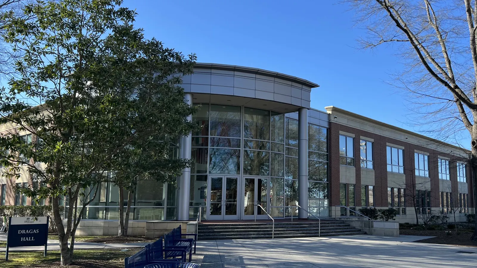 Dragas Hall at Old Dominion University, a brick and glass building with a curved glass entrance and steps, under a blue sky
