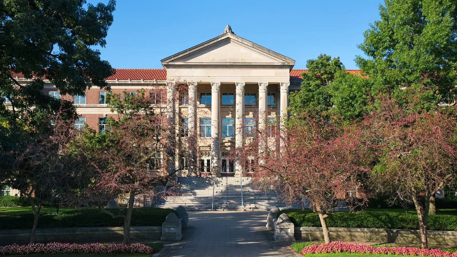 Hovde Hall of Administration framed by trees and flower beds at Purdue University in West Lafayette, Indiana