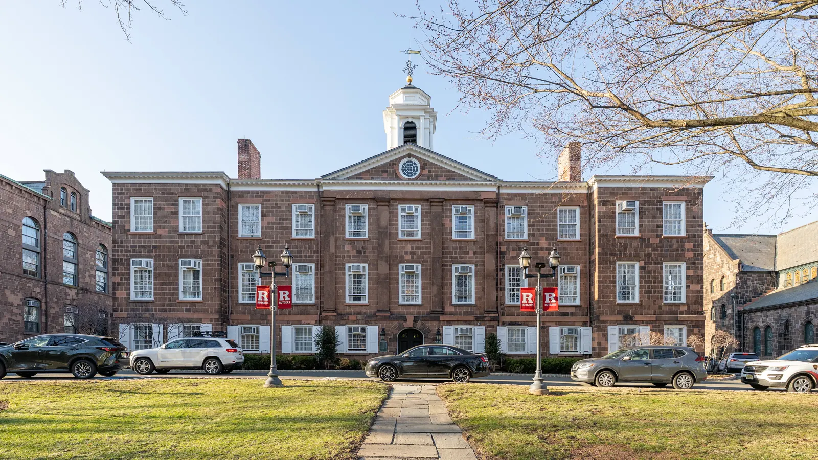 Old Queens, a brownstone building with a white cupola, behind a lawn at Rutgers University-New Brunswick