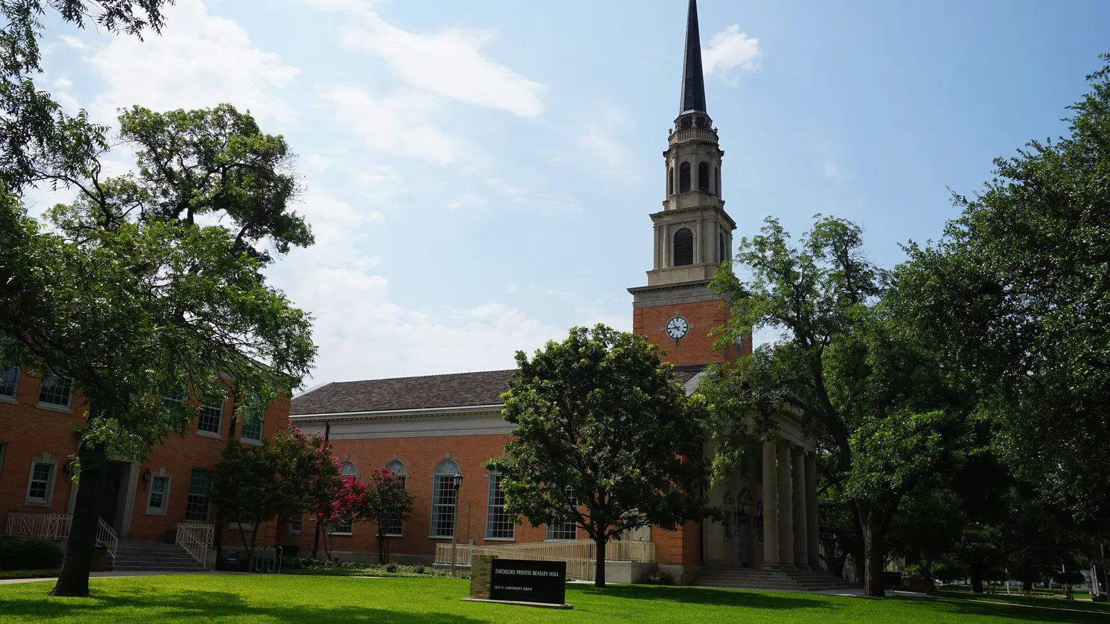 Robert Carr Chapel and its brick bell tower beside a shaded lawn at Texas Christian University in Fort Worth, Texas