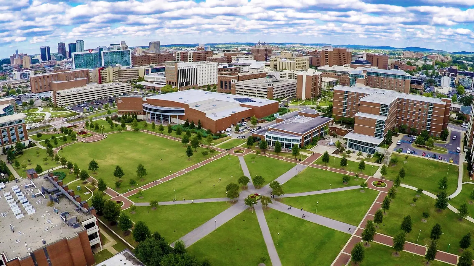 An aerial view of the Campus Green with its crossing walkways and surrounding buildings at the University of Alabama at Birmingham, with downtown Birmingham behind