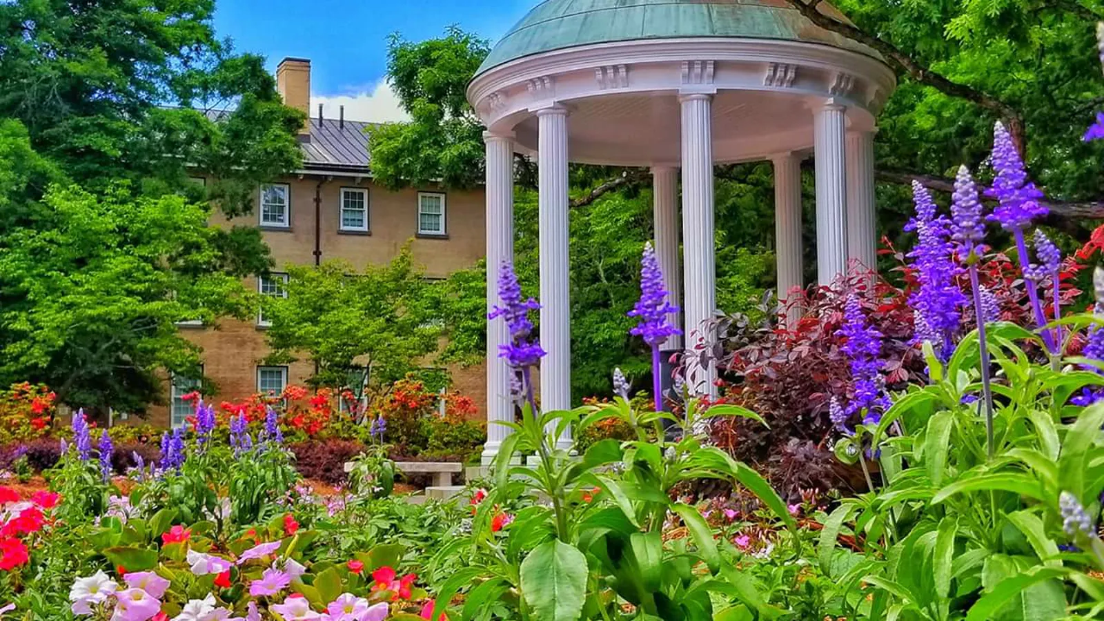 The Old Well among flower beds at the University of North Carolina at Chapel Hill, with Old West behind it
