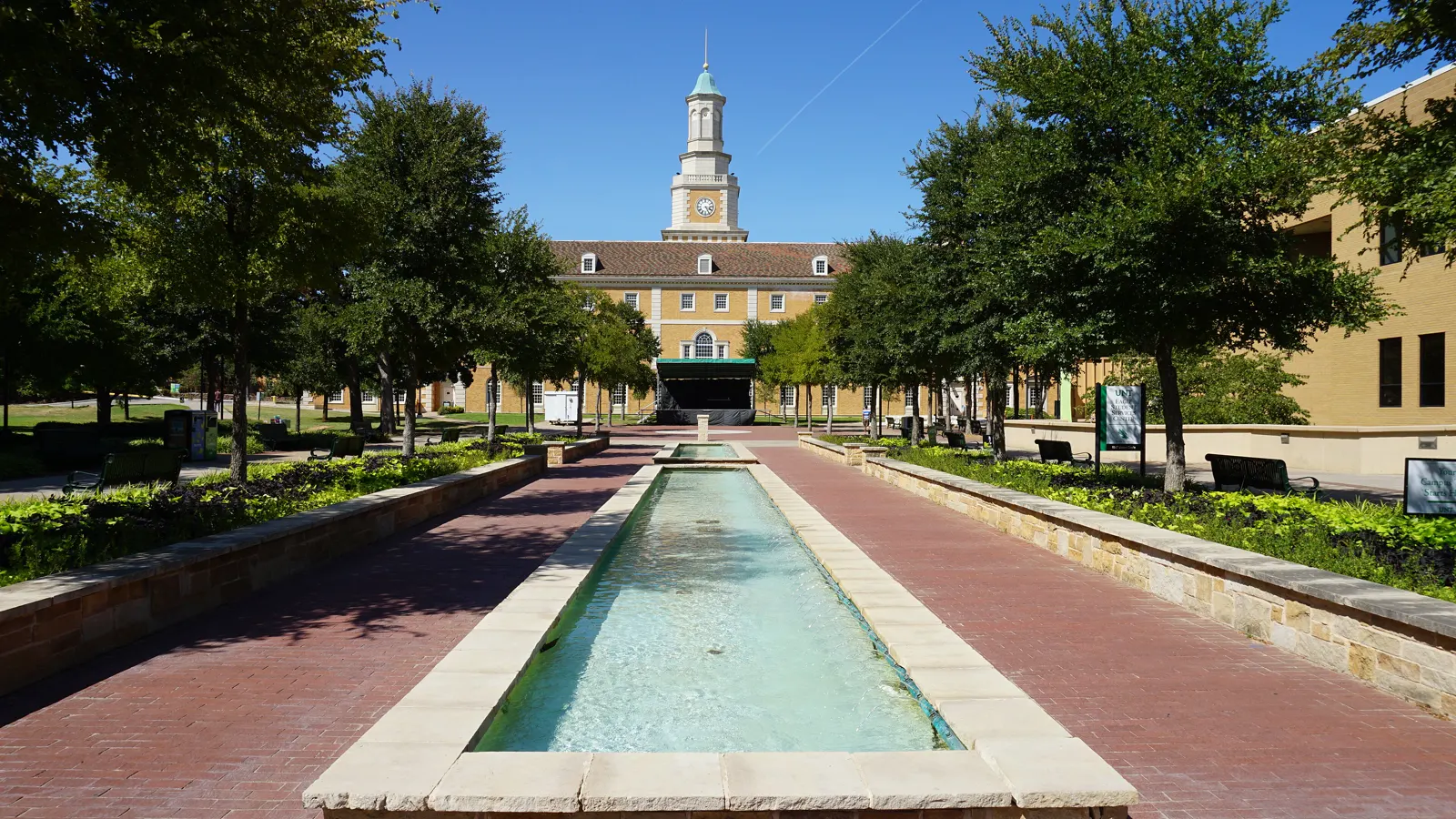 The Hurley Administration Building and its clock tower seen past a reflecting pool on the University of North Texas campus in Denton, Texas