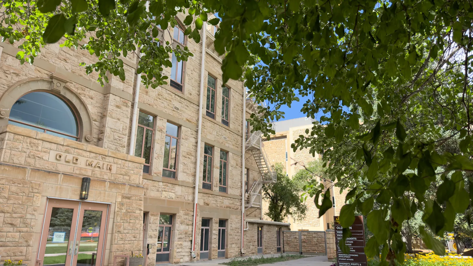 The sandstone entrance of Old Main framed by tree branches at the University of Wyoming in Laramie, Wyoming