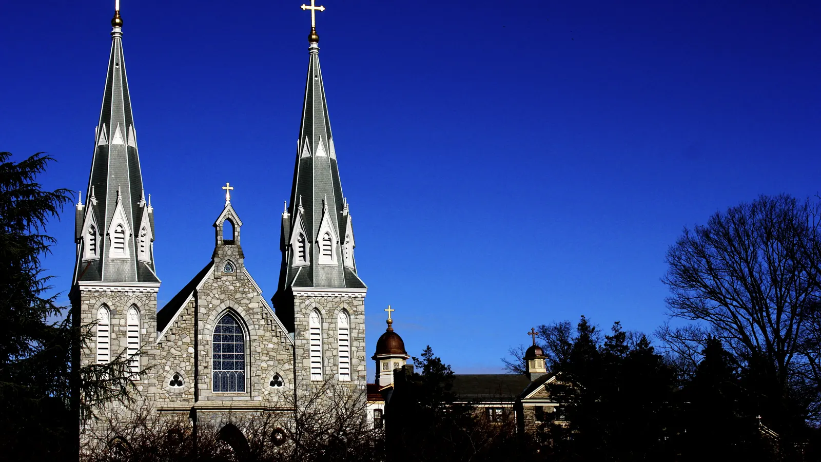 The twin spires of the Church of St. Thomas of Villanova against a deep blue sky on Villanova University's campus